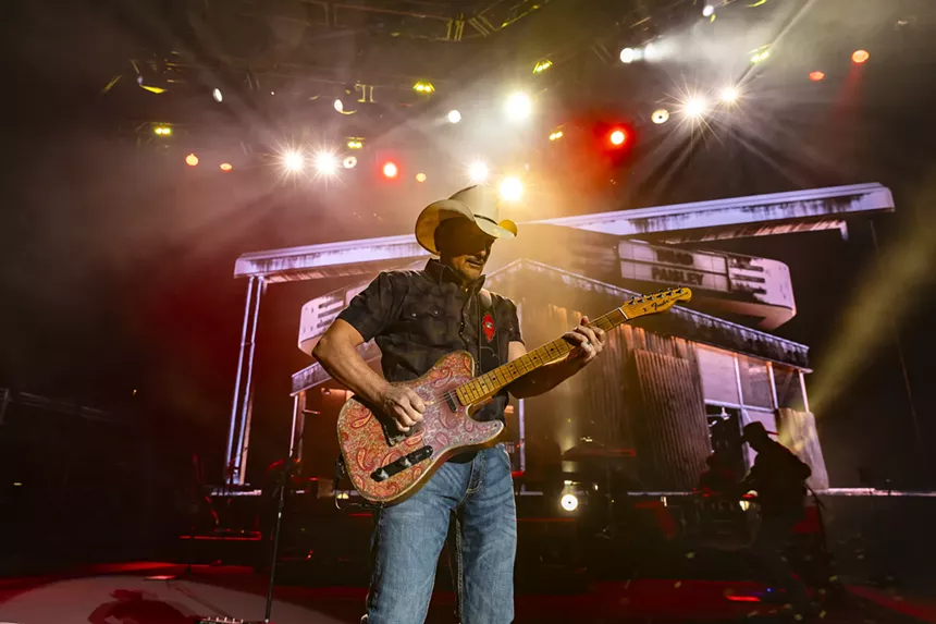A photo showing Brad Paisley on stage at Red Rocks with stage lights behind him.