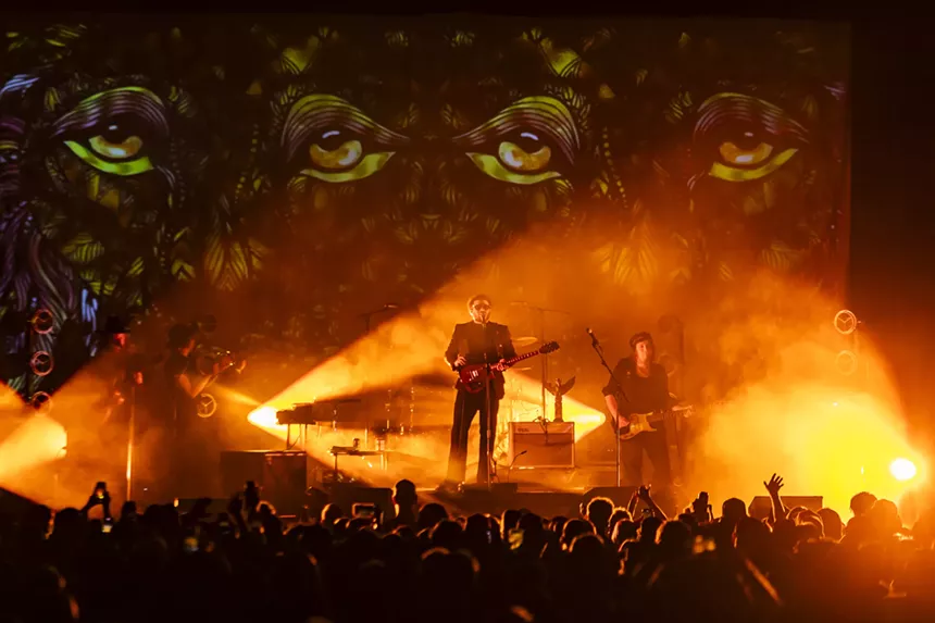 Dope Lemon on stage with stage lights shining on him, with a visual behind him.