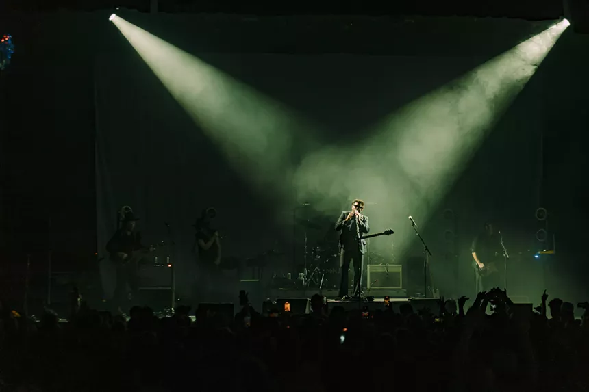 A photo showing Dope Lemon on stage with spotlights shining on him.