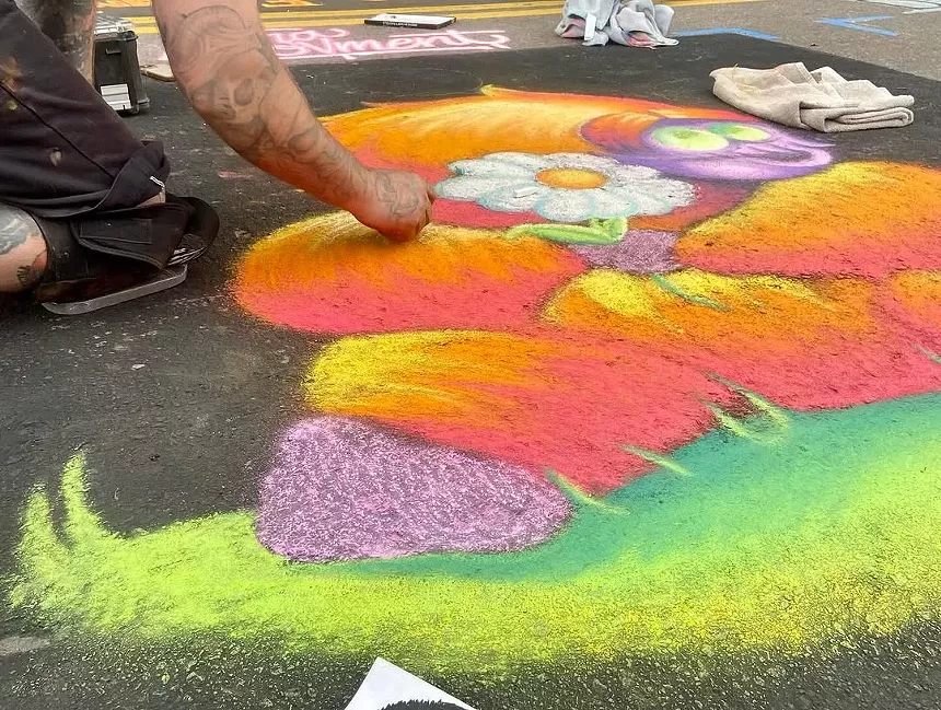 An artist uses chalk to create a street painting.