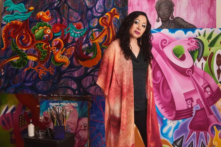 A woman stands in front of colorful artwork
