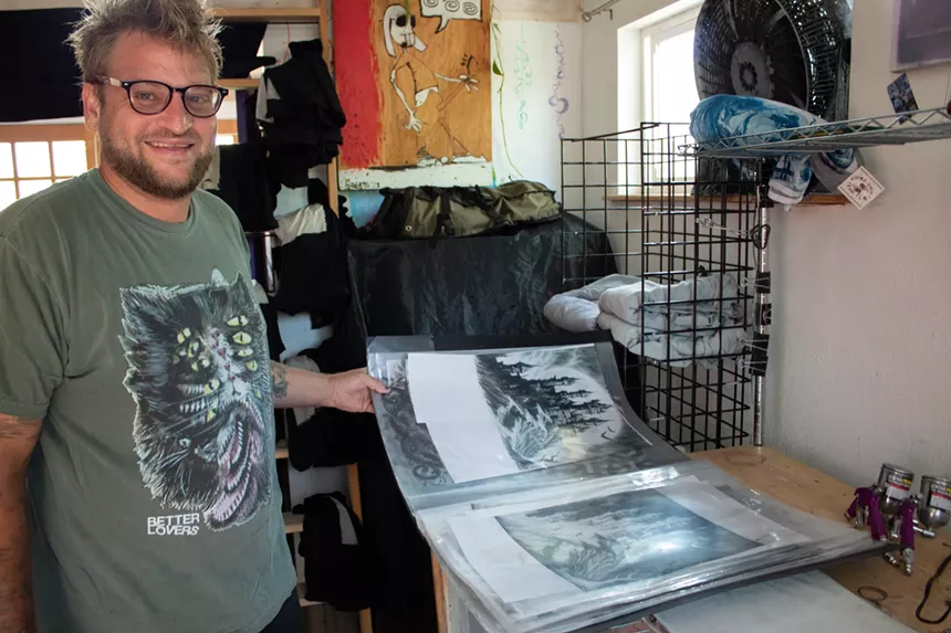 A man stands with a large book of design work.