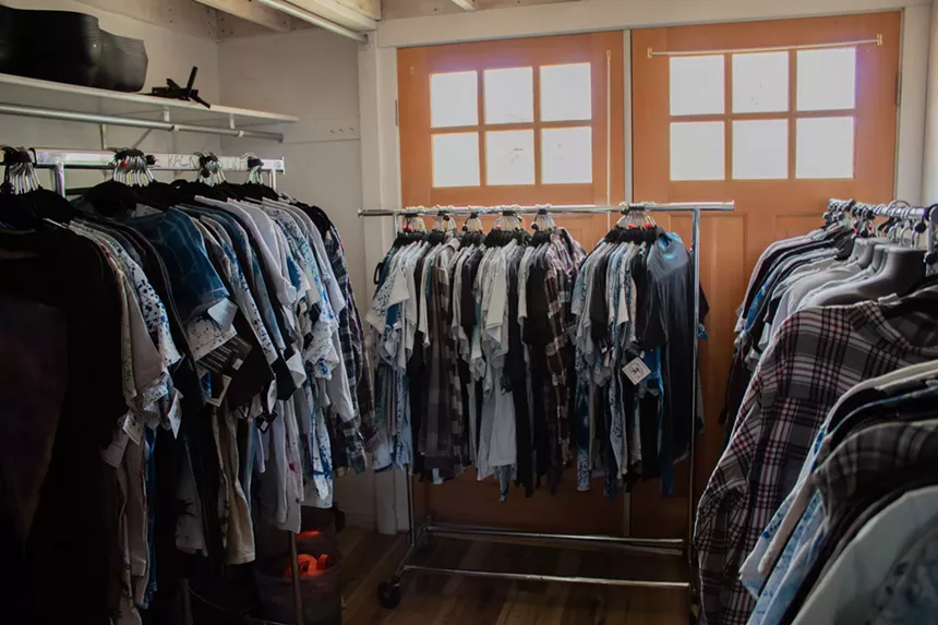Many multicolored shirts hang on a rack.