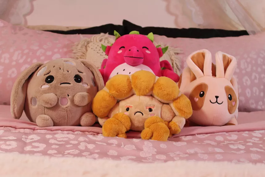 Four plush toys stand up on a pink bed.