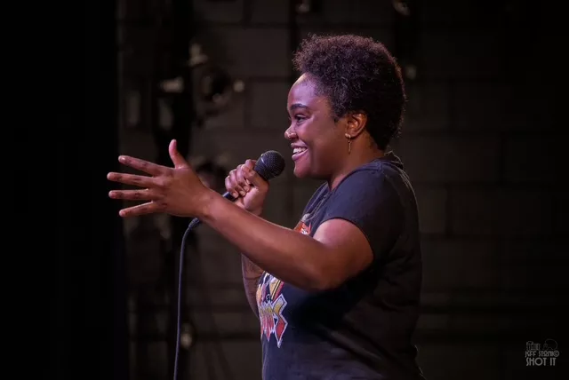A comedian speaks into a microphone onstage.