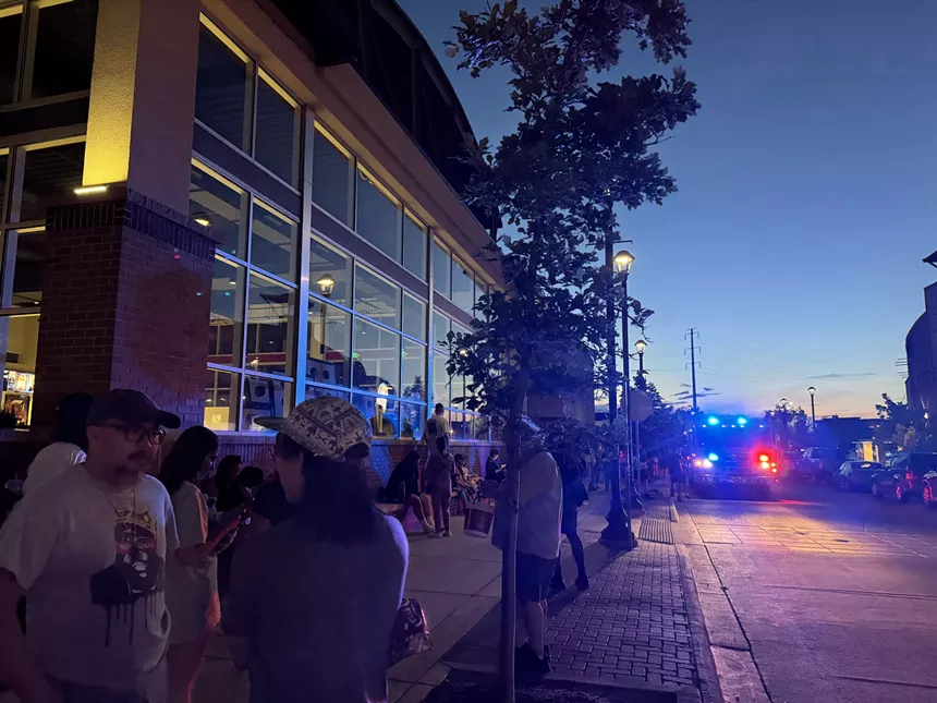 people stand in line outside movie theater during fire alarm