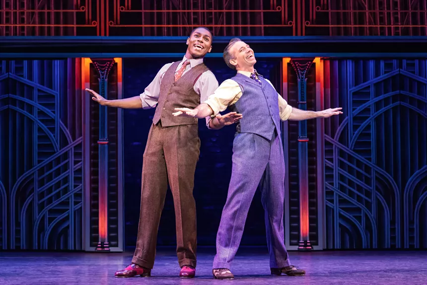In a dance number, two people strike a pose with their arms out.