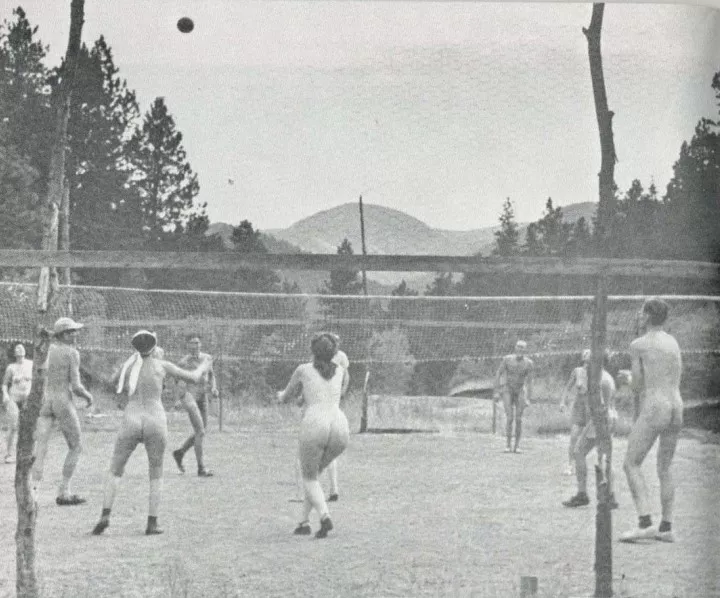 A black and white photo of naked people playing volleyball