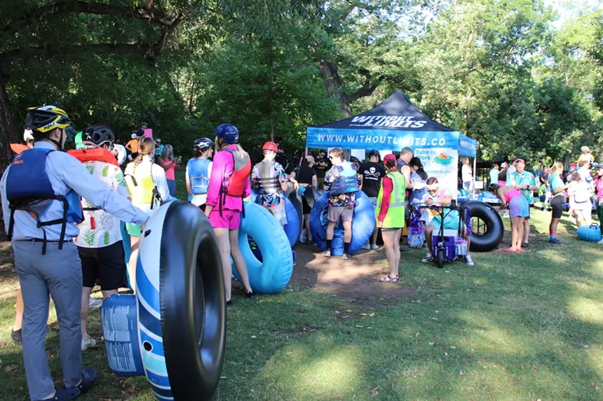 Crowd of people with tubes stand in line.