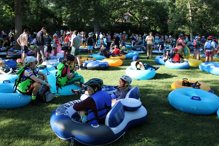 A group of people sit and stand with inner tubes in a park.