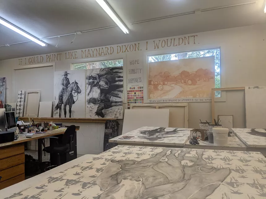 A table and wall of art in a studio