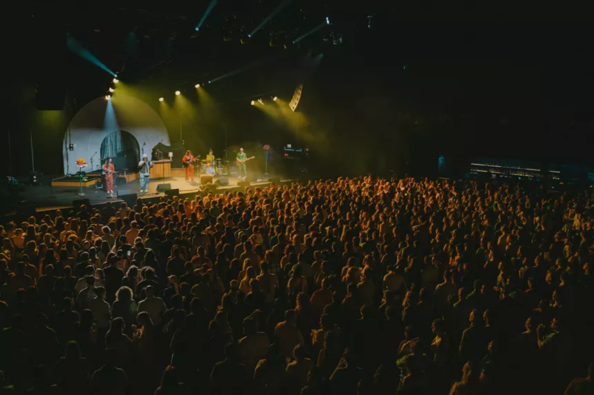 band on stage performing to a sold-out crowd in an indoor venue