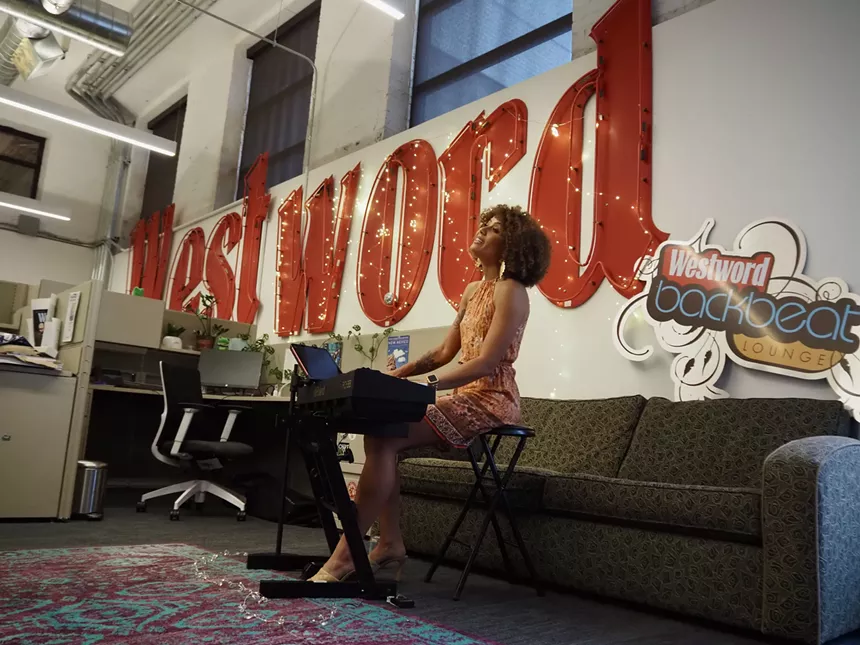 woman playing piano and singing in the Denver Westword office