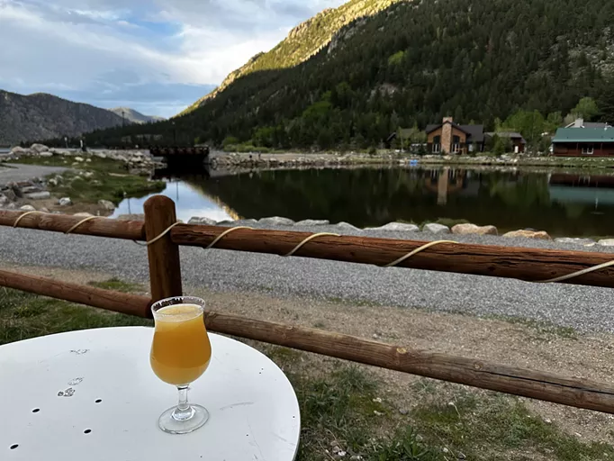 Glass of beer on a table in front of mountains and a lake
