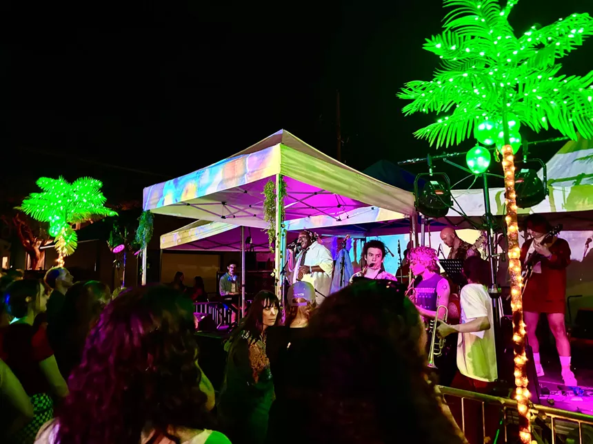 band playing an outdoor show under a tent at night
