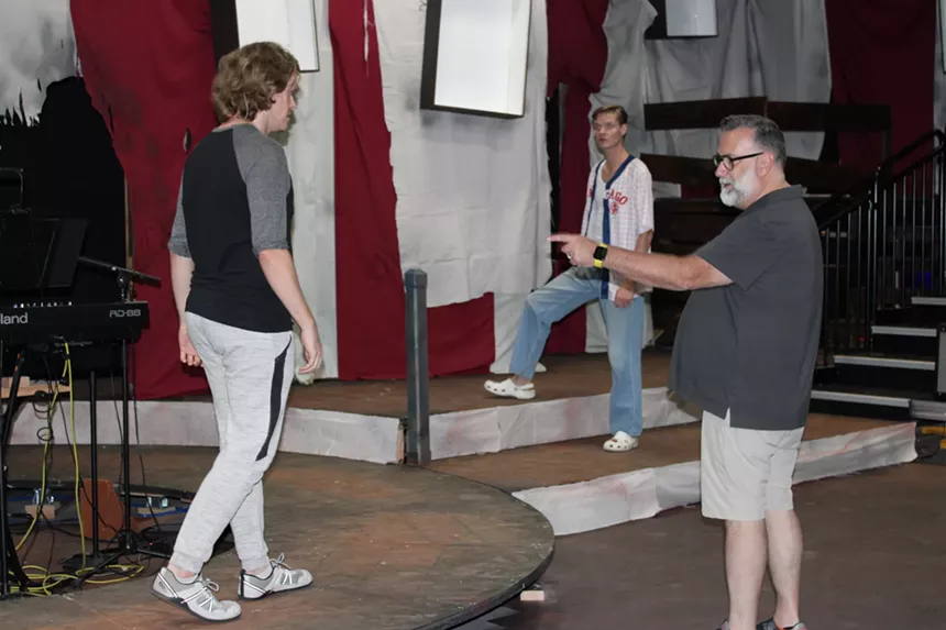 A director blocks a scene onstage with an actor.