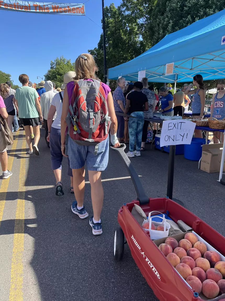 A person pulls a wagon full of peaches.