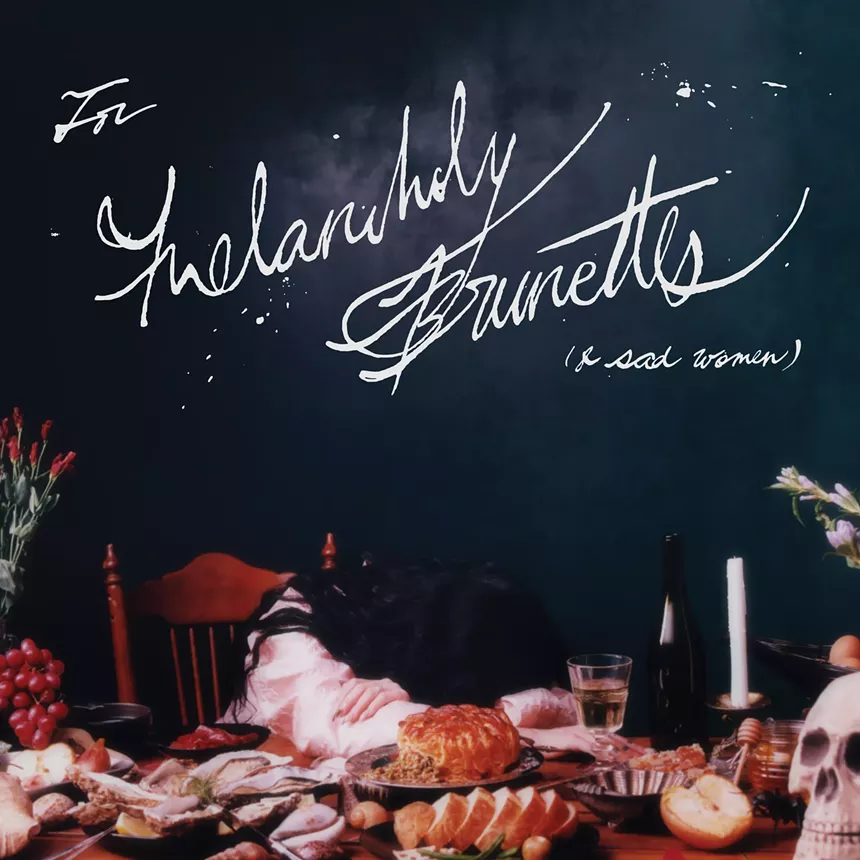 An album cover for Melancholy Brunettes (and Sad Women) with Michelle Zauner sitting at a dinner table with a skull and several food items on a dark green-blue background