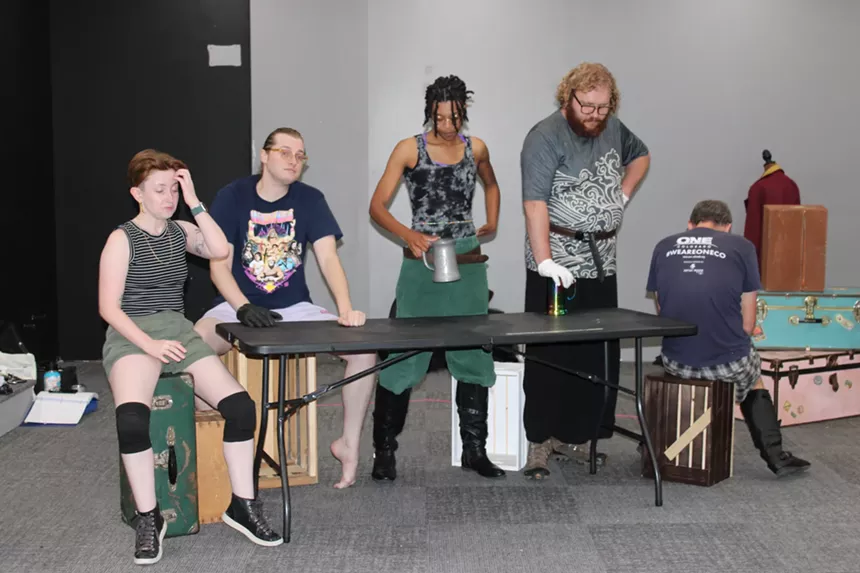 Cast members sit and stand during a rehearsal break.