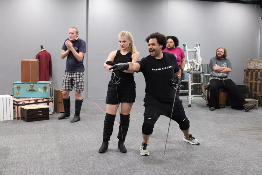 The cast practice a large group scene.