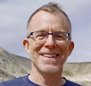 A man in a blue shirt smiling