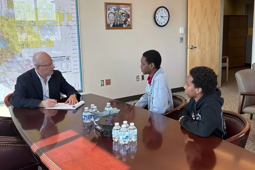 A man talks to a couple of teenagers.