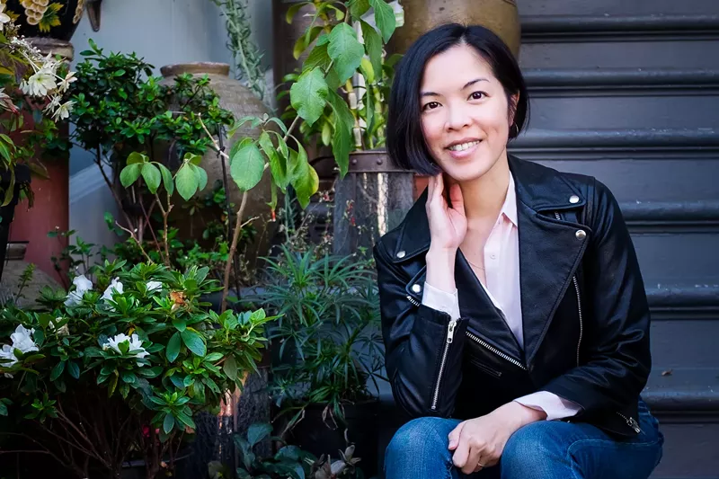 Image: woman posing for a photo next to plants