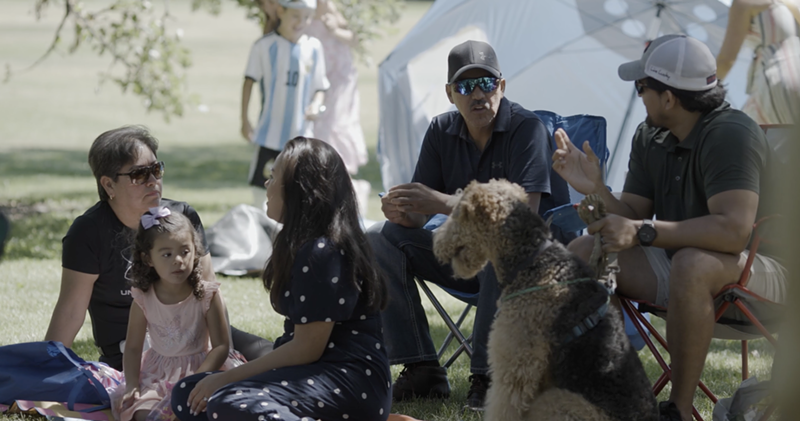 Image: People and a dog sit together in the grass