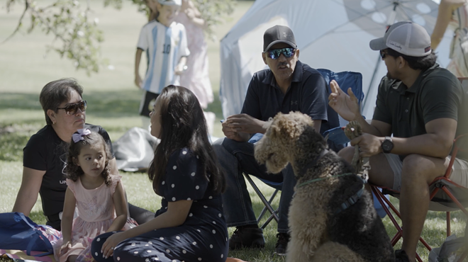 People and a dog sit together in the grass