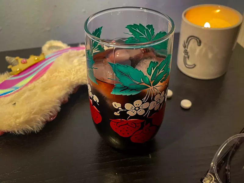 Image: a red drink in a glass next to a candle