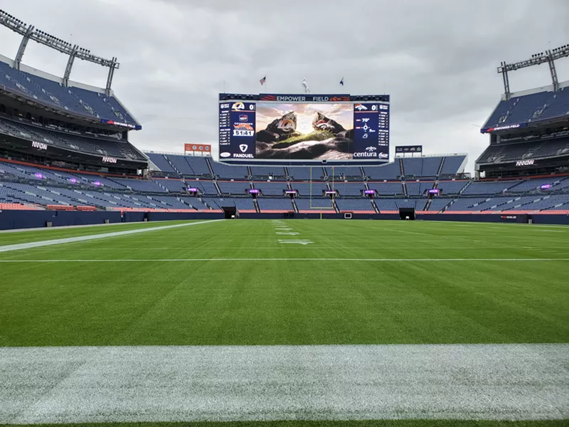 Image: A giant scoreboard at the end of a stadium with a grassy field.