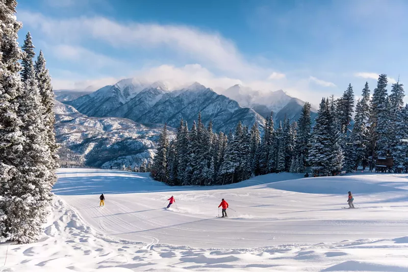 Image: A group of people backdropped by mountains while skiing at Purgatory Resort