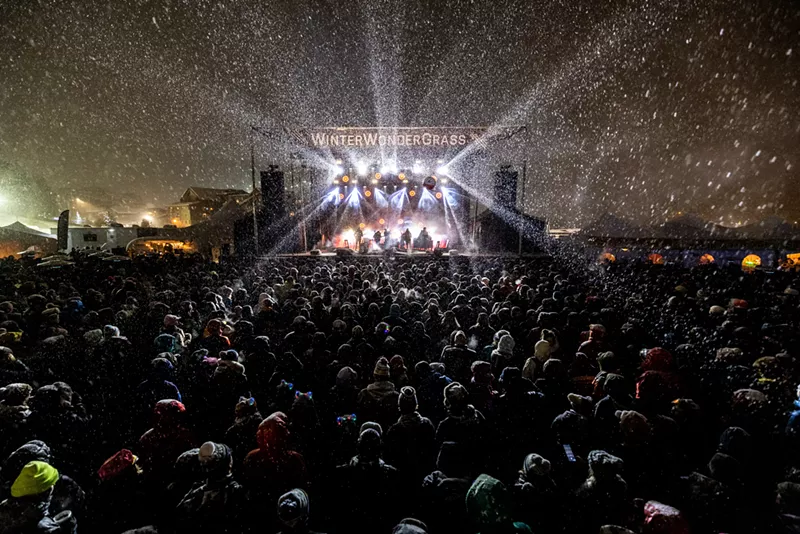 Image: a stage with the words WinterWonderGrass is surrounded by an audience in the snow