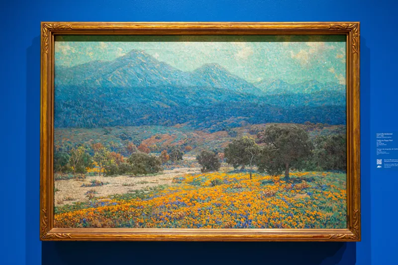 Image: A colorful painting of a landscape against a blue wall