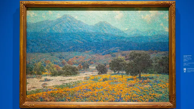 A colorful painting of a landscape against a blue wall