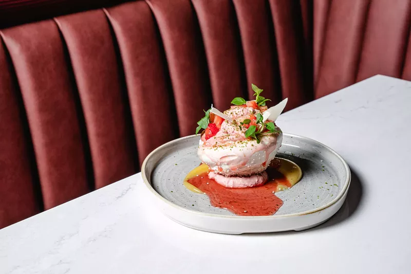 Image: A coconut pavlova from Ajax, backdropped by a berry-colored booth
